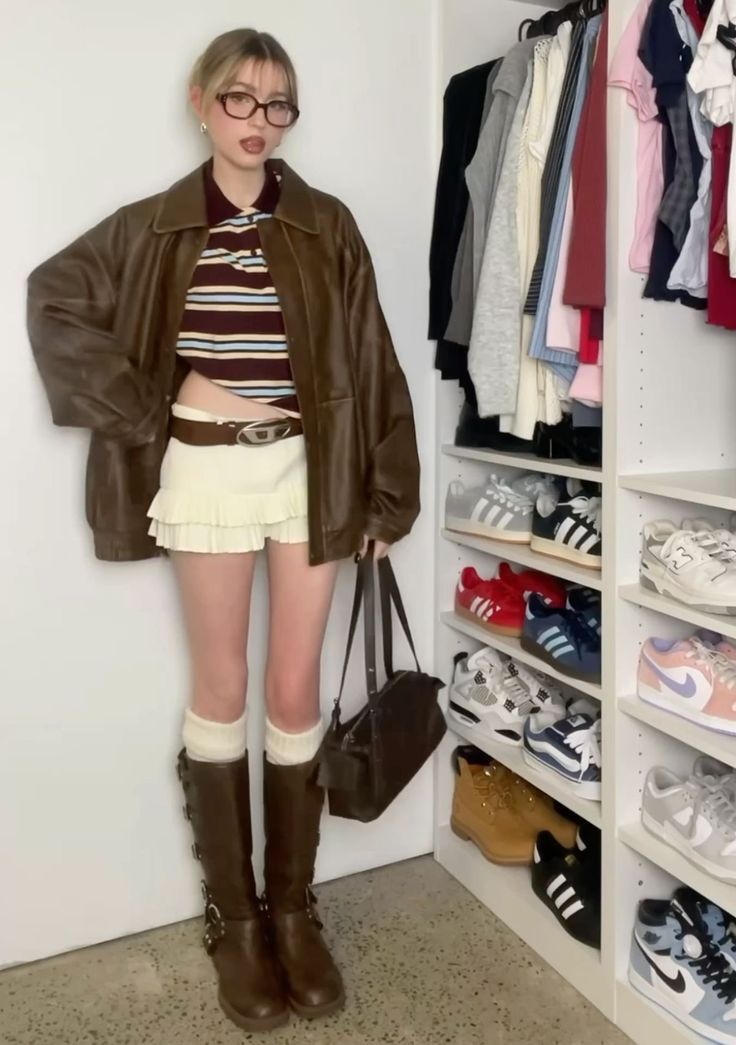 Woman in a brown leather jacket and mini skirt standing in front of a wardrobe