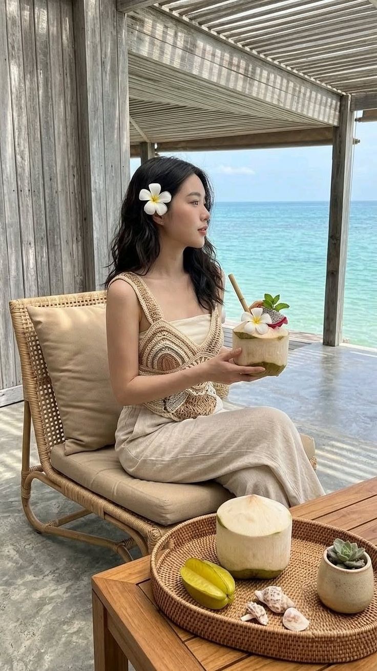 Woman in a crochet top holding a coconut drink on a beachside patio
