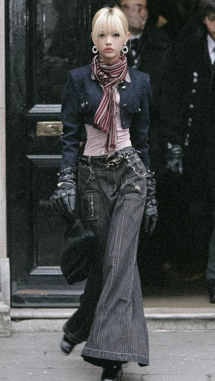 Person with blonde hair and a striped scarf wearing a cropped jacket and pinstripe pants