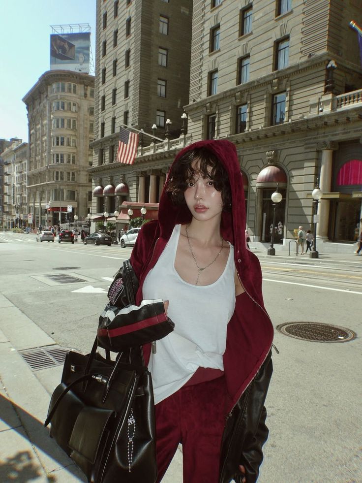 Woman in a red hoodie and white tank top on a city street