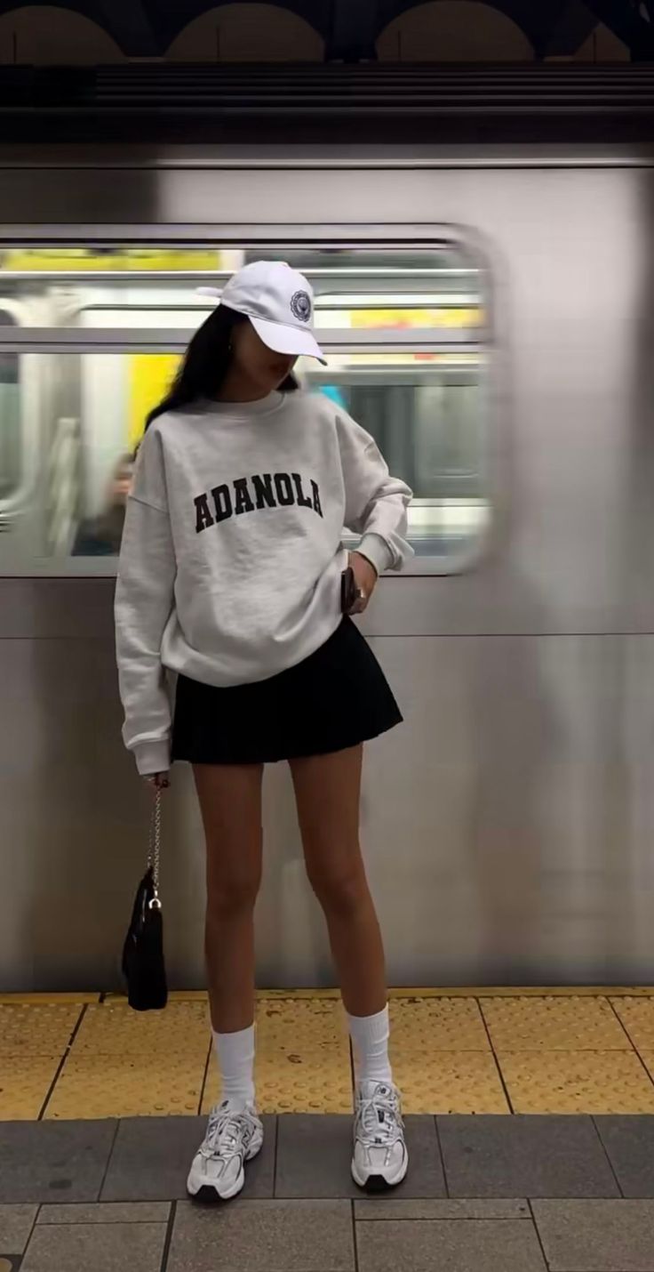 Person in a white sweatshirt and black mini skirt at a subway station