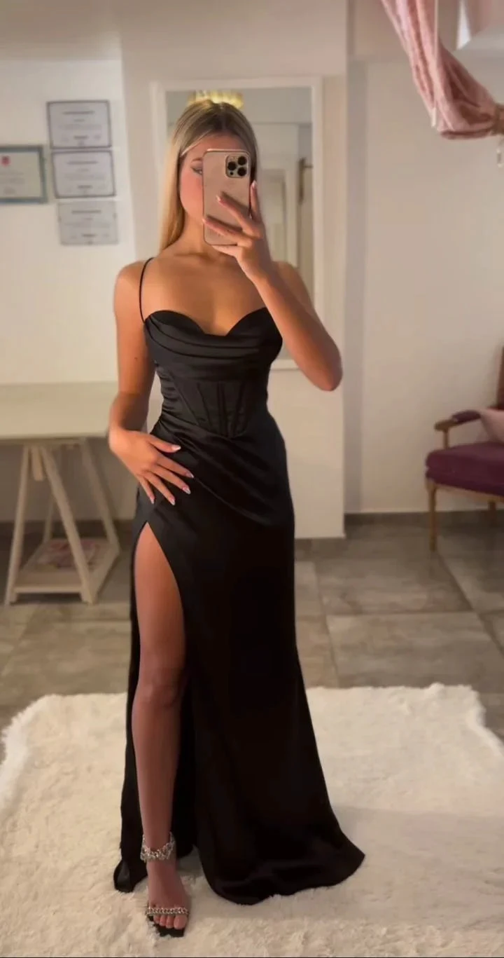 Woman in a black dress with a high slit taking a mirror selfie