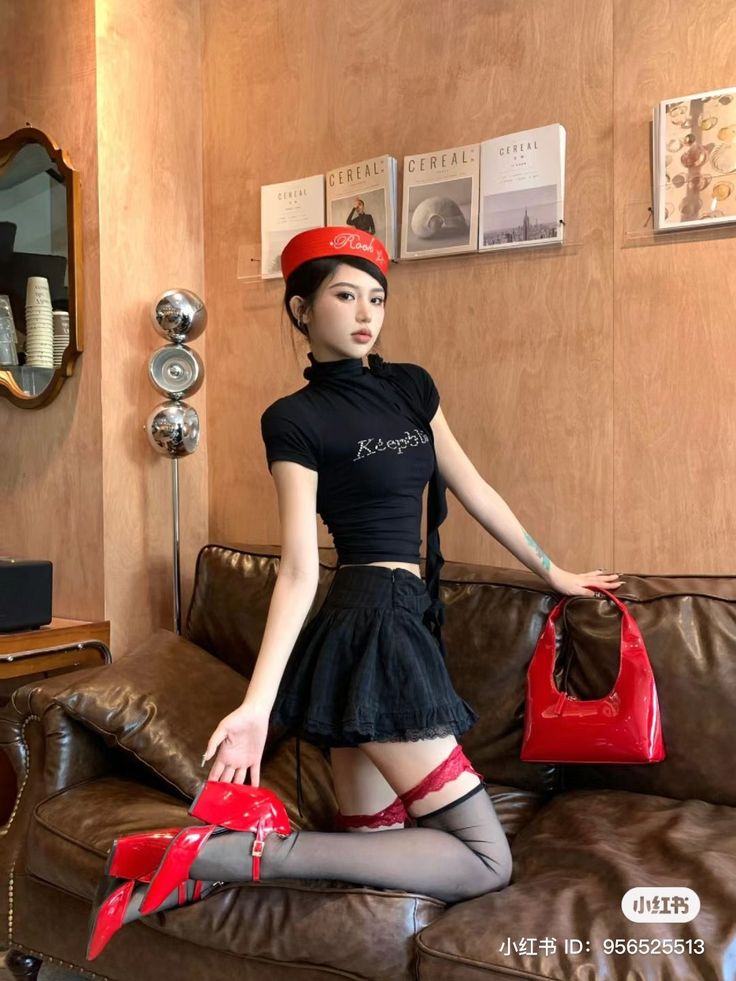 Woman in a black top and mini skirt with red accessories posing on a couch