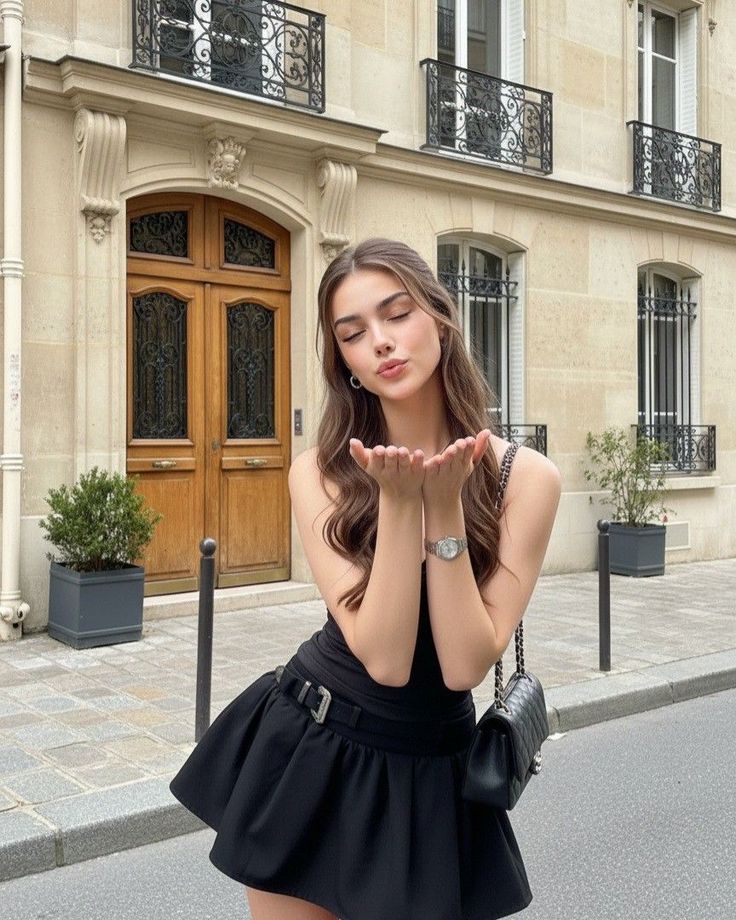 Woman in a black dress blowing a kiss on a city street