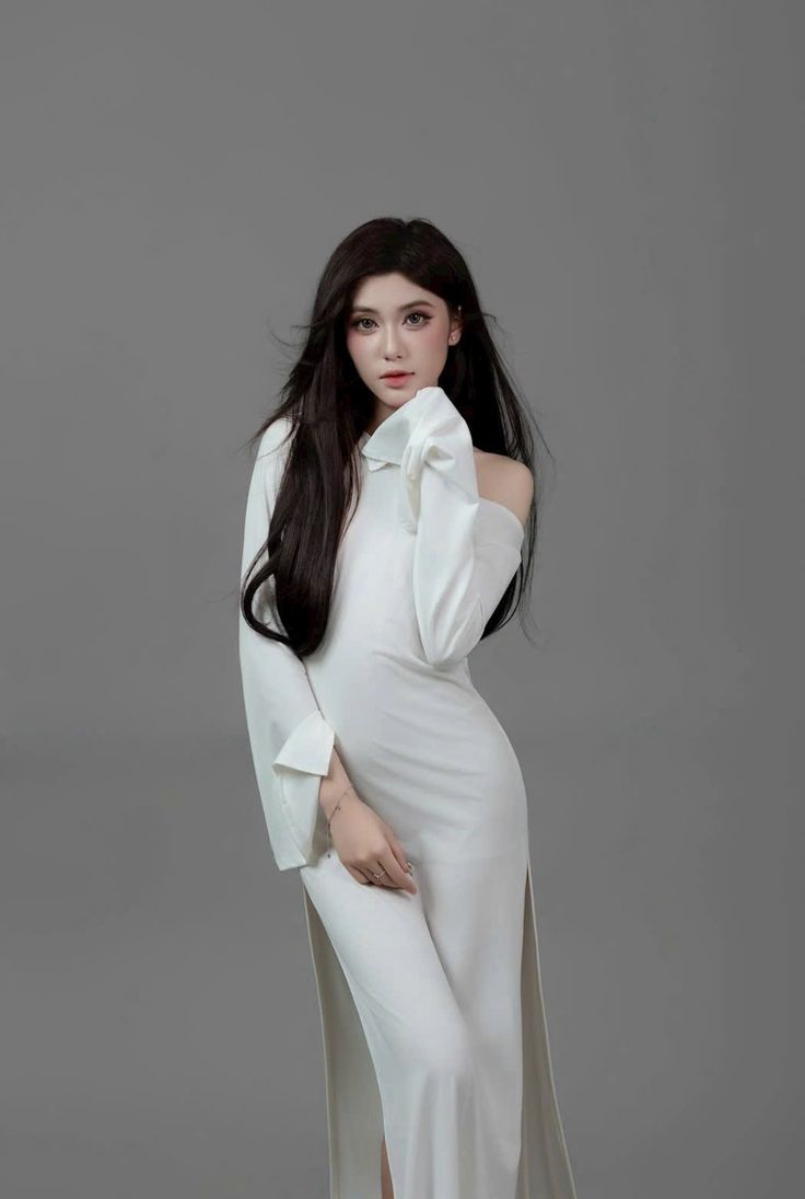 Woman with long black hair in a white off-shoulder dress in a studio