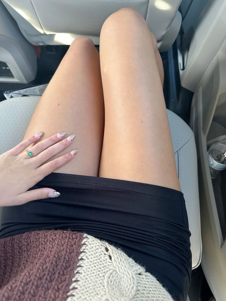 Person in a short black skirt and knitted sweater in a car interior