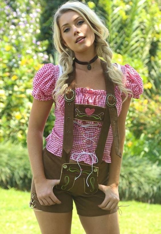 Woman with blonde braids wearing a dirndl and gingham shirt outdoors