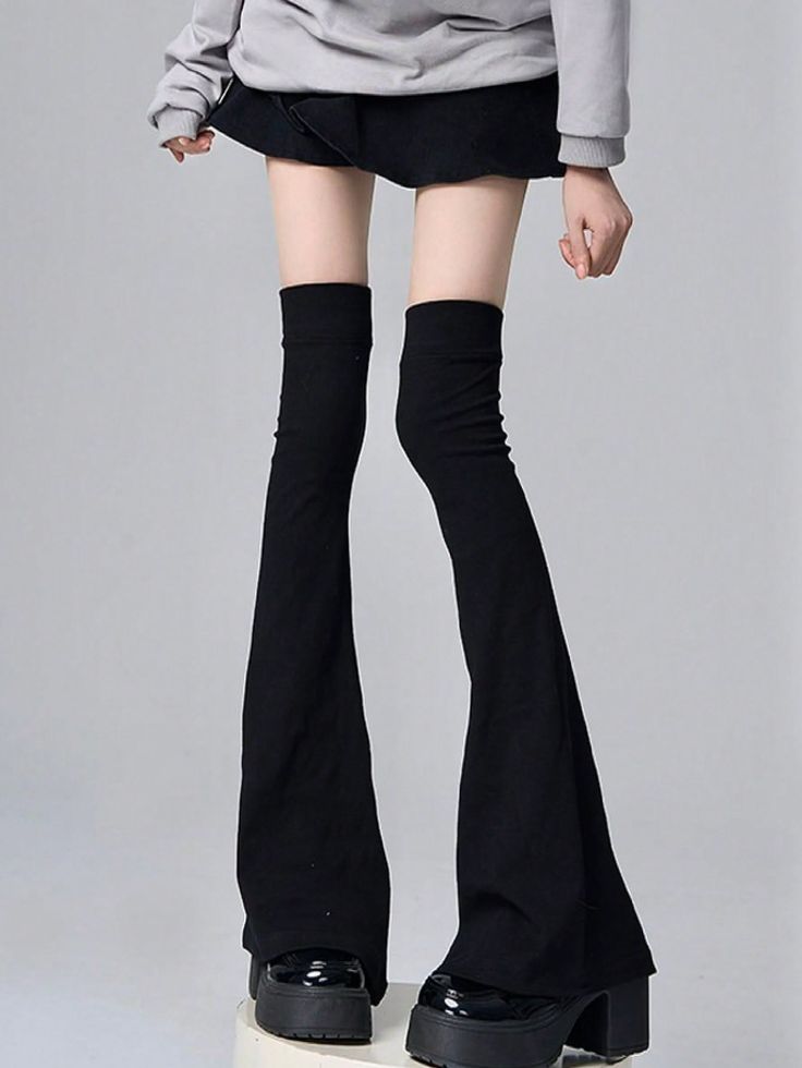 Person in a gray hoodie, black skirt, and platform shoes with exposed thighs