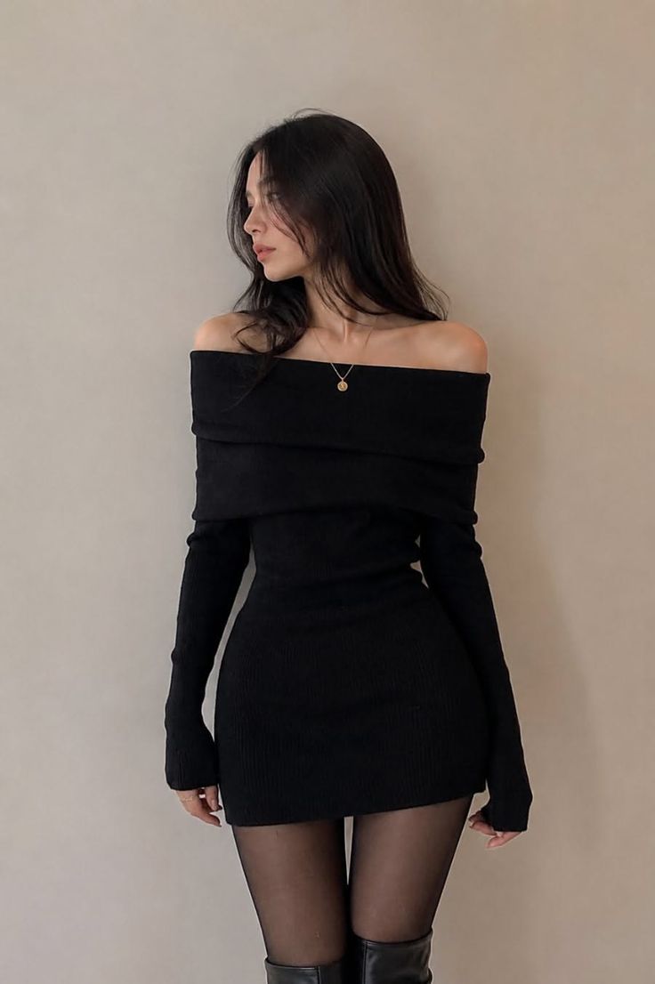 Woman in a black off-shoulder dress and tights posing indoors