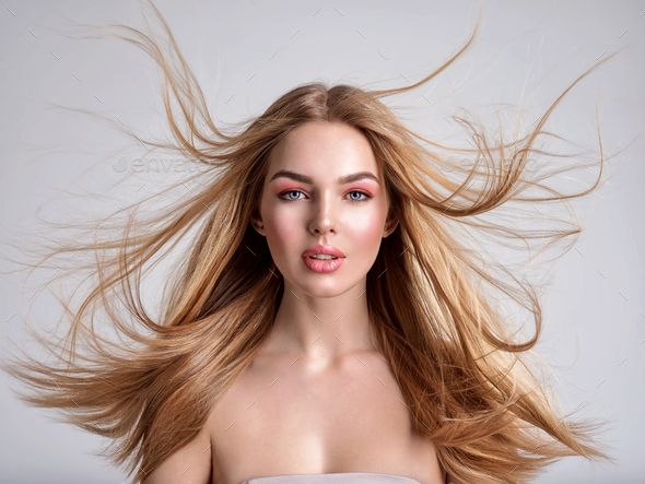 Woman with long blonde hair flying around her face, wearing pink makeup