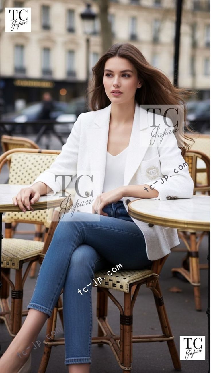 Woman with long brown hair wearing a white blazer and jeans at an outdoor cafe