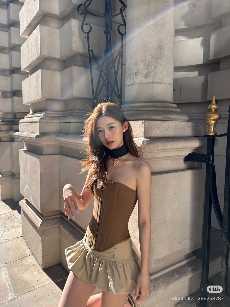 Woman in a brown corset top and beige mini skirt outdoors with sunlight