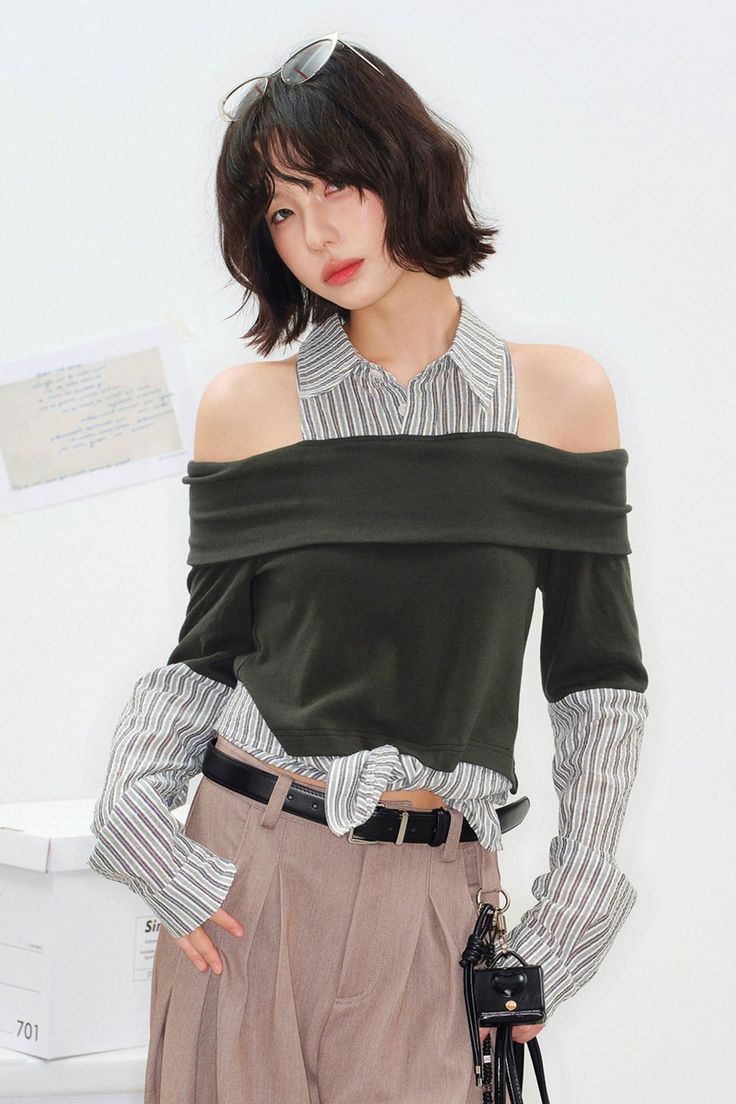 Woman with short hair wearing an off-shoulder top over a striped shirt