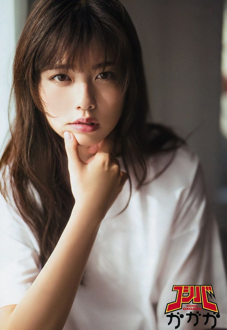 Woman with long brown hair and a white shirt, hand on chin, looking at viewer