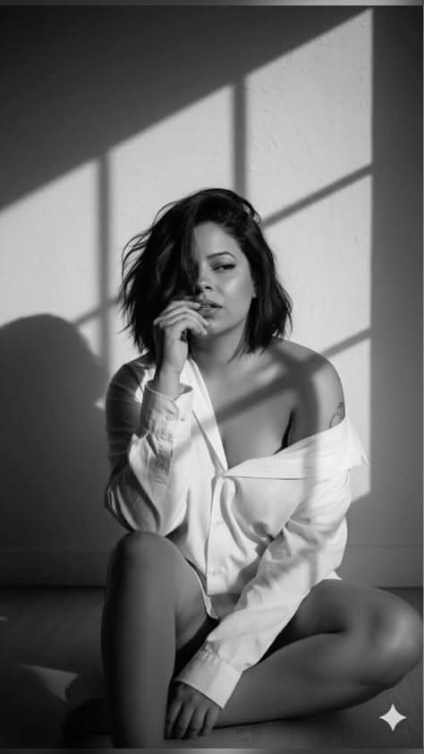 Woman in an unbuttoned white shirt with dramatic lighting in black and white