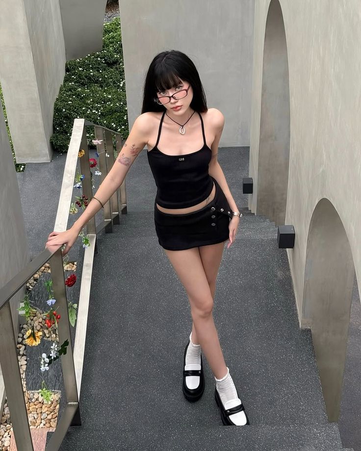 Woman in a black mini skirt and halter top posing on outdoor stairs