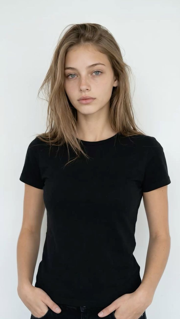 Young woman with long hair and blue eyes wearing a black t-shirt against a white background