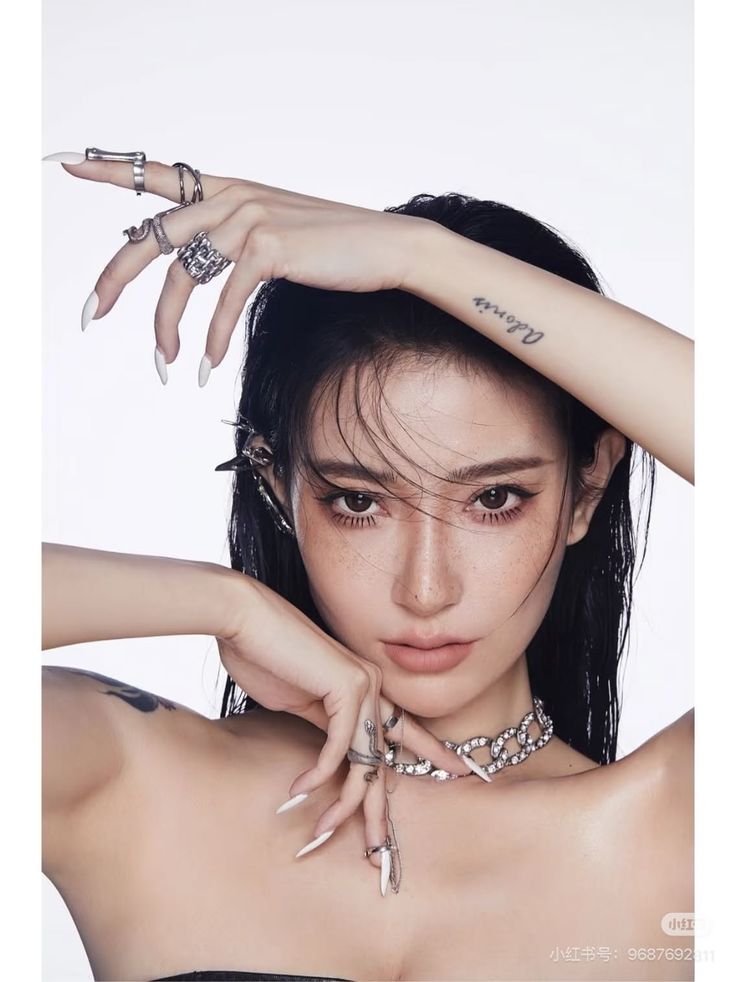 Woman with long black hair and freckles wearing silver jewelry and long nails