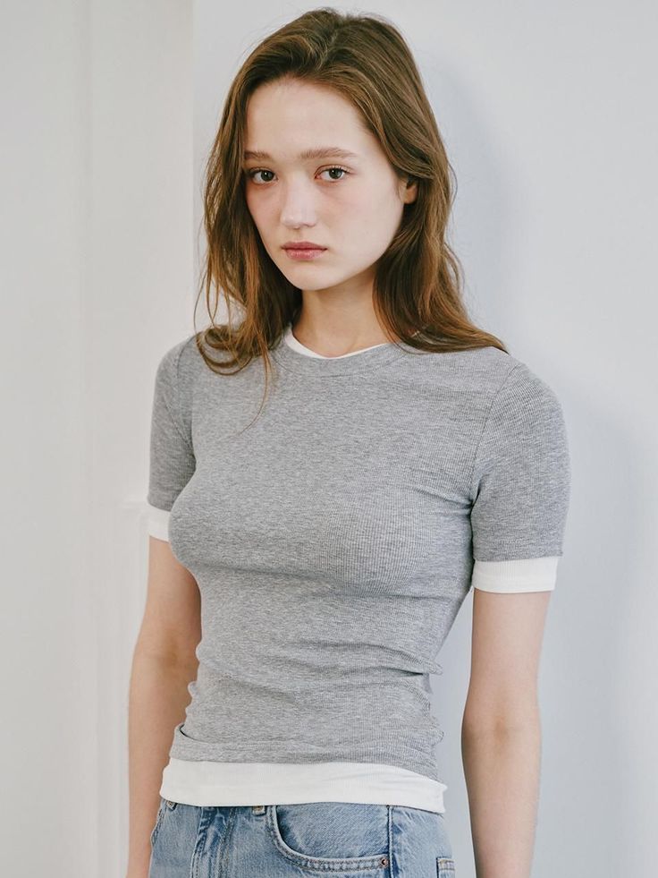 Woman with long hair wearing a grey t-shirt and jeans indoors