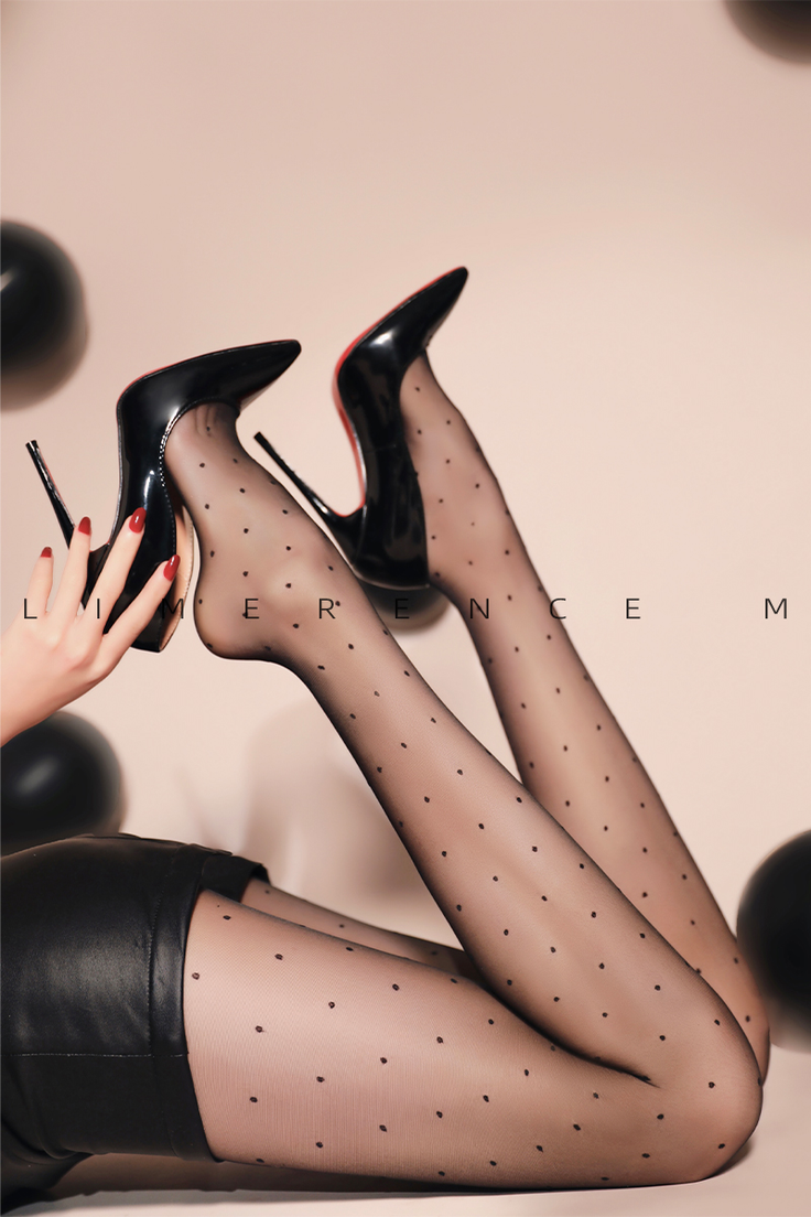 Woman's legs in polka dot stockings and high heels, with a hand touching a shoe