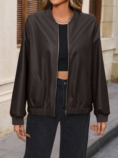 Woman in a dark brown bomber jacket and black crop top with jeans