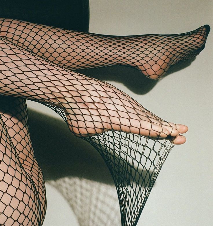 Legs in fishnet stockings with one foot stretching the material