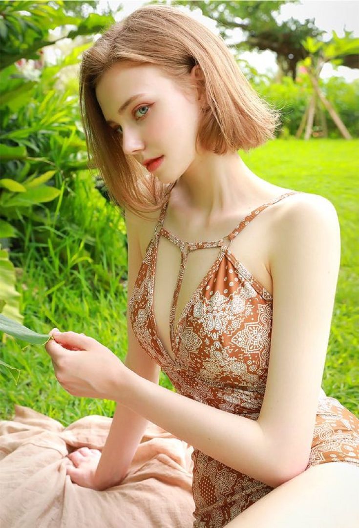 Woman in a patterned swimsuit sitting on a blanket outdoors