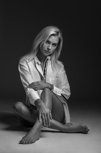 Blonde woman in a white shirt sitting on the floor in a studio