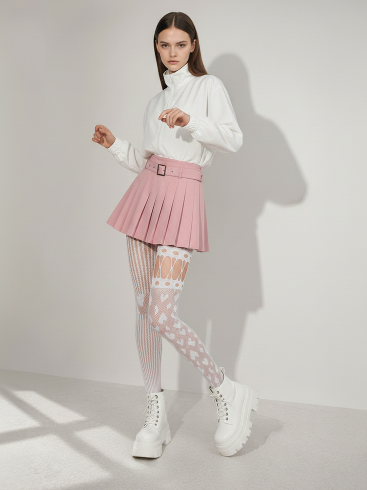Woman in a pink pleated skirt, white jacket, and patterned tights in a studio