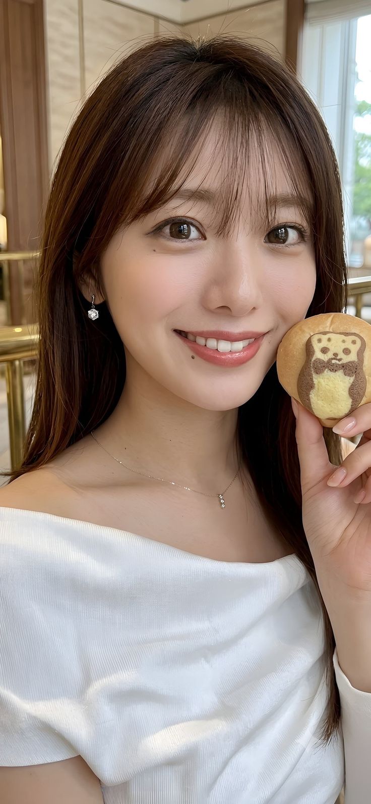 Woman with long brown hair smiling and holding a bear-shaped cookie