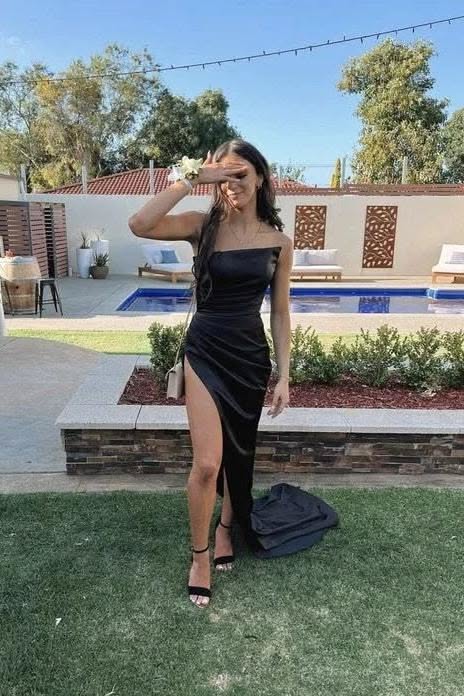 Woman in a black strapless dress with a high slit posing outdoors