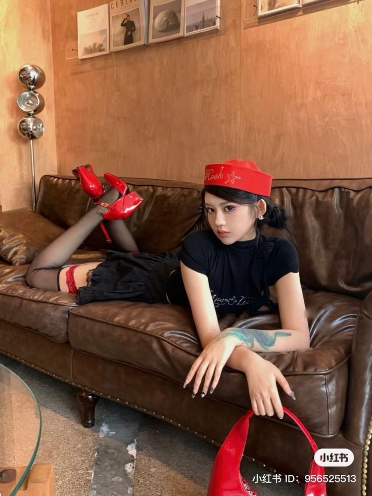 Woman in a red hat and black stockings posing on a brown leather couch