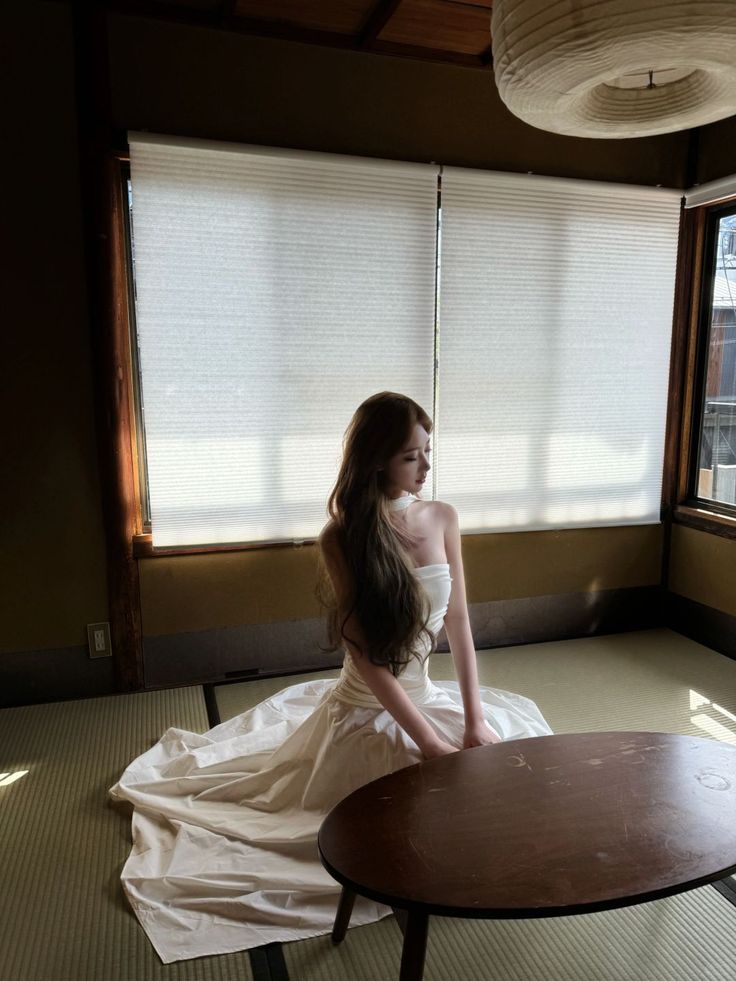 Woman with long hair in a white dress sitting on a tatami mat in a Japanese room