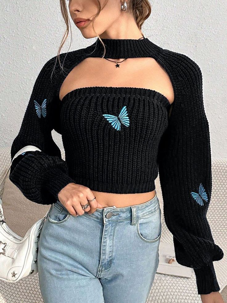 Woman in a black knit top with butterfly embroidery and blue jeans