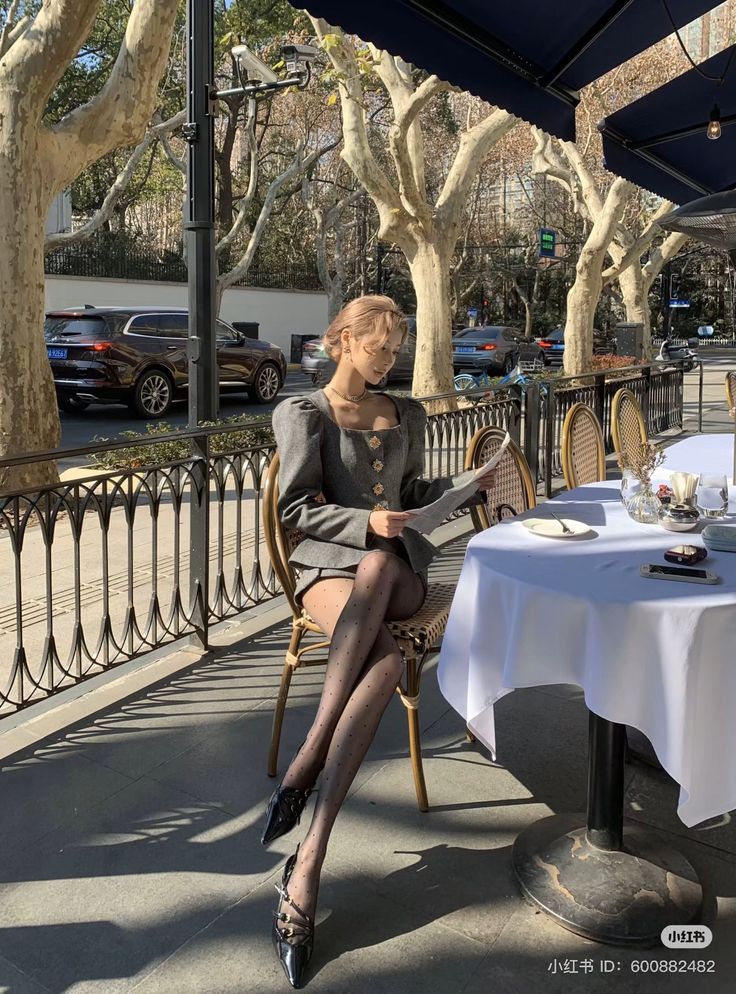 Woman in a grey suit and polka dot tights sitting at an outdoor cafe