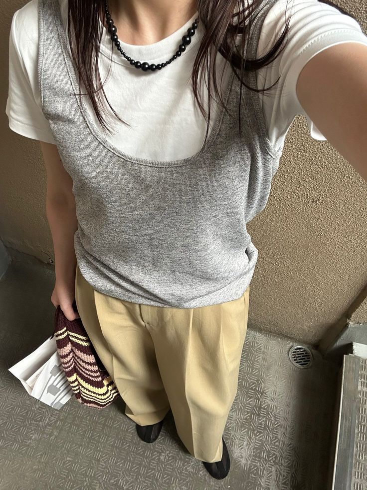 Person in a gray tank top over a white t-shirt and khaki pants