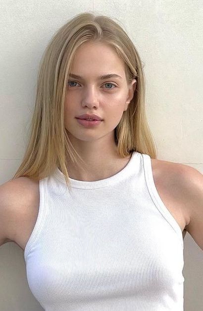 Young woman with blonde hair and blue eyes wearing a white tank top
