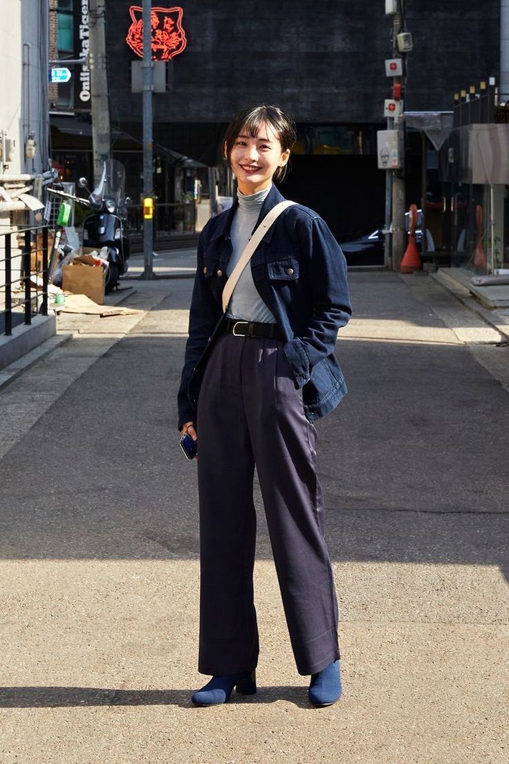 Woman in a denim jacket and wide leg pants standing on a street