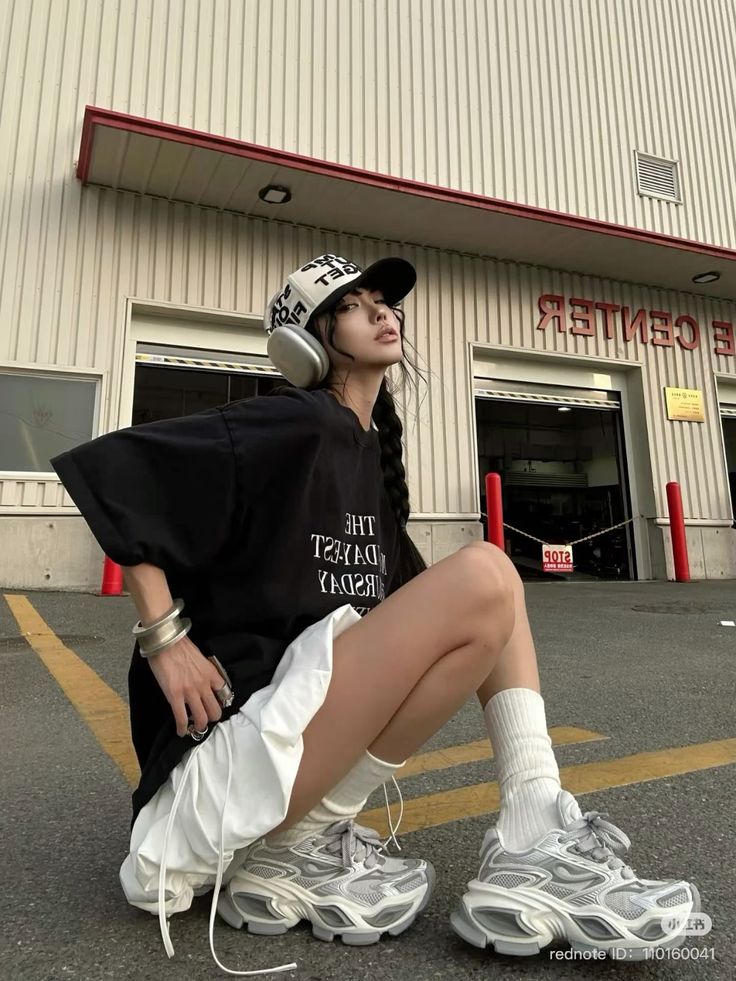 Woman in a baseball cap and headphones squatting outdoors
