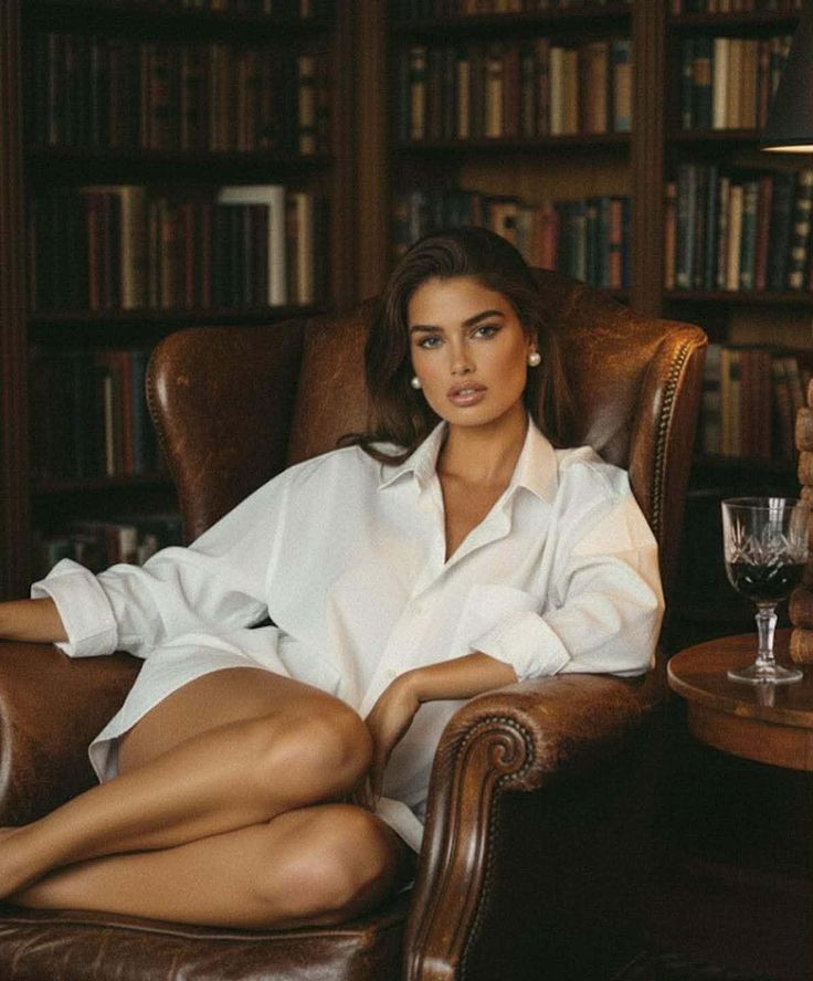 Woman in a white shirt sitting in a leather armchair in a library