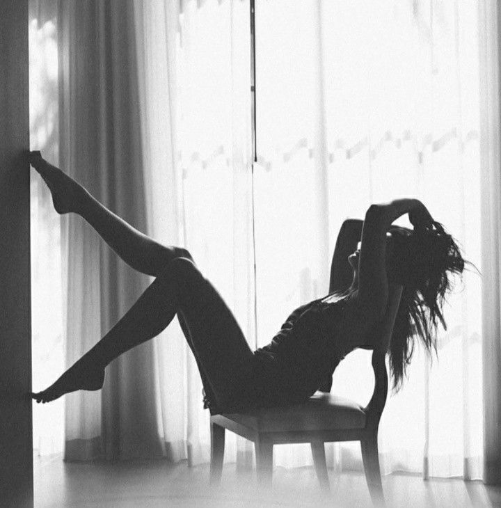 Woman in silhouette posing on a chair against a bright window