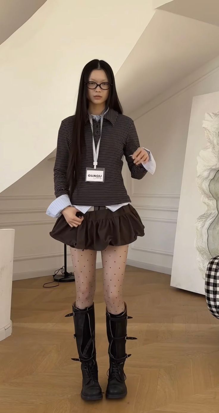 Woman with long hair and glasses wearing a striped shirt, ruffled skirt, and combat boots