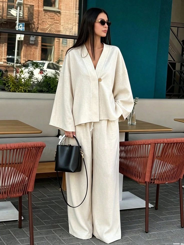 Woman in a cream matching set and sunglasses at an outdoor cafe