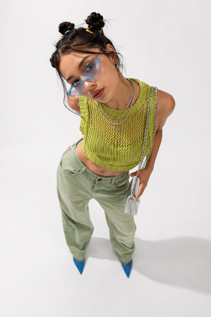 Woman with space buns and blue sunglasses wearing a green knit top and pants