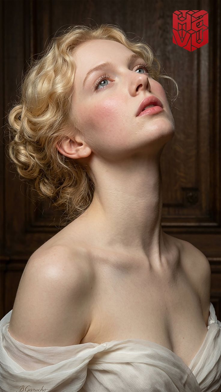 Woman with blonde curly hair looking up, draped in white fabric
