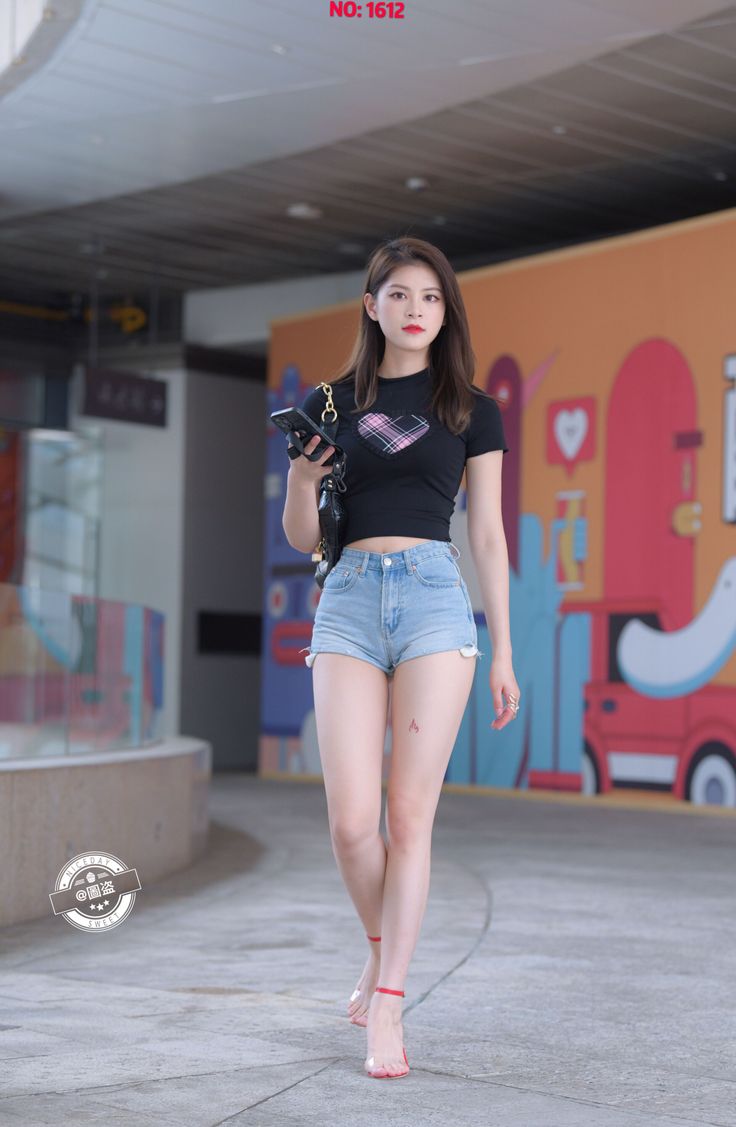 Woman in denim shorts and a black crop top walking outdoors