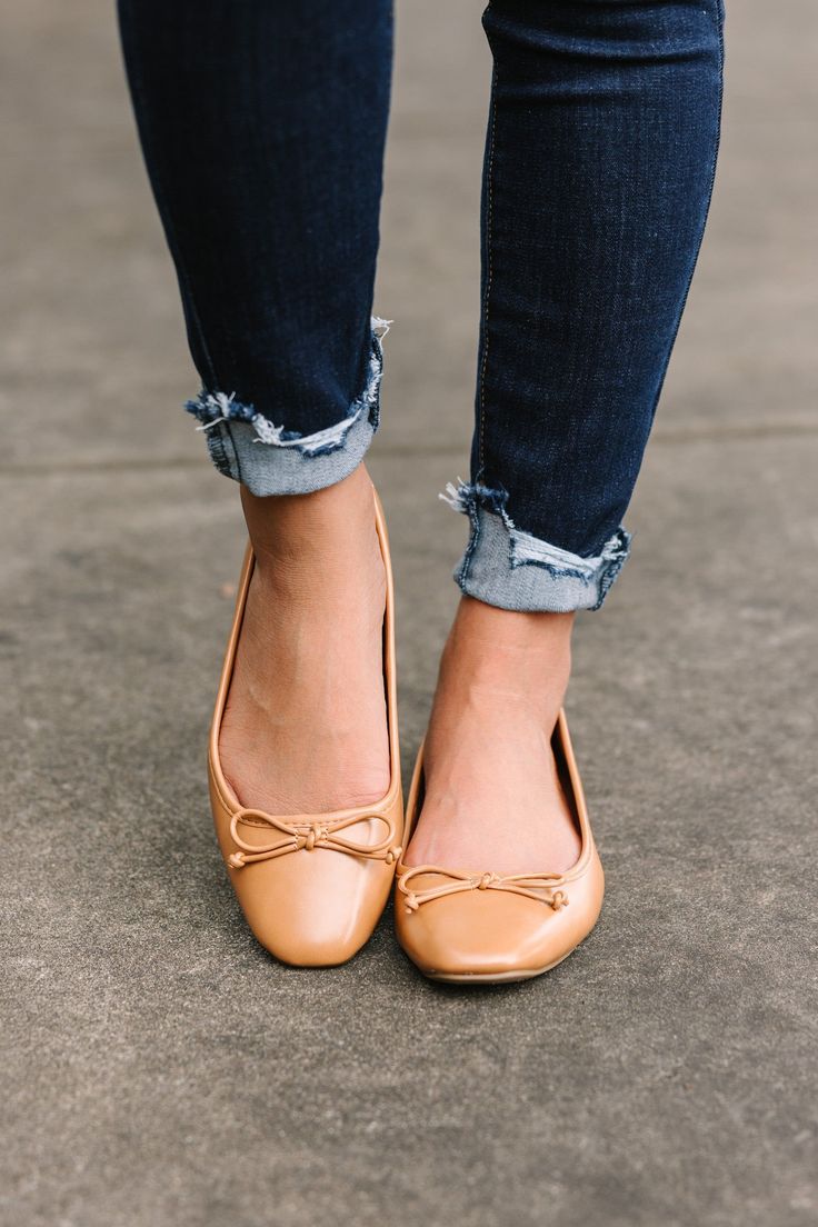 Person wearing blue jeans with distressed cuffed hems and tan ballet flats