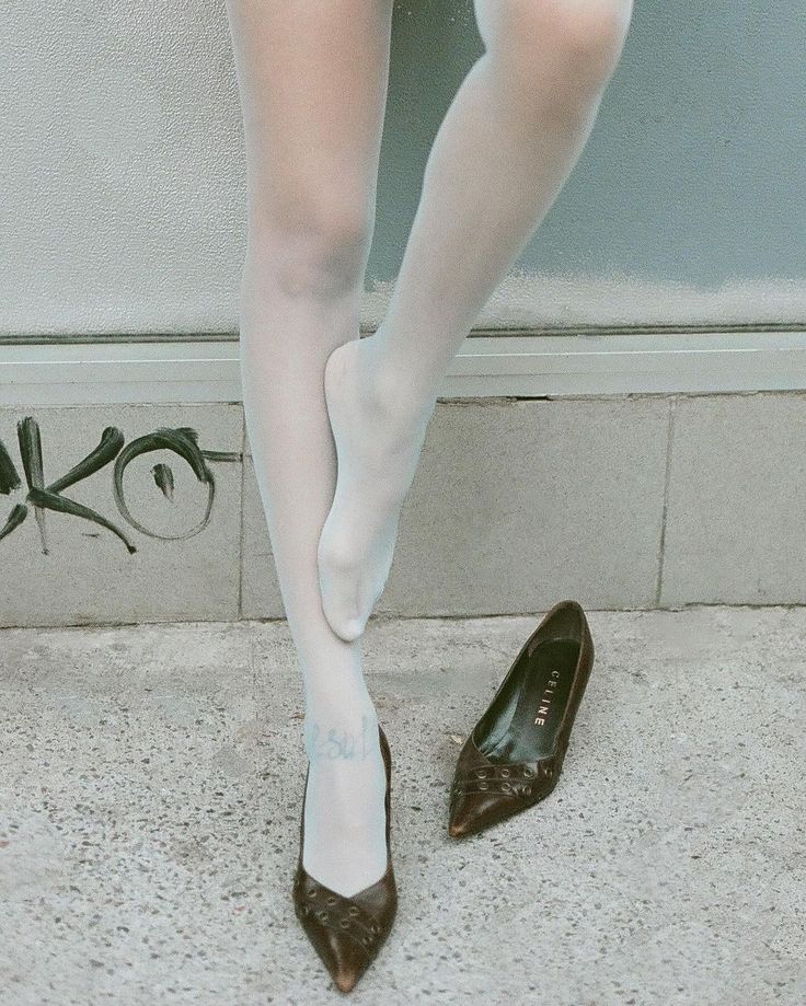 Person wearing white tights and brown high heels with one shoe off