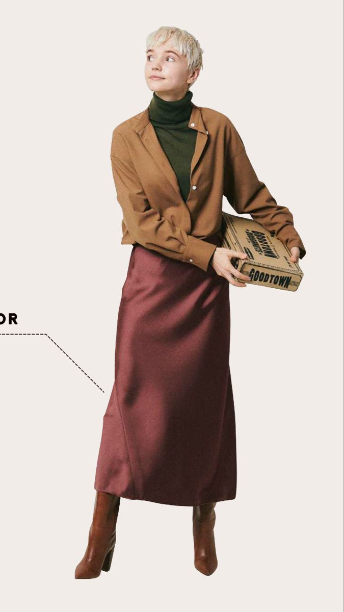 Woman with short blonde hair wearing a brown shirt and long skirt