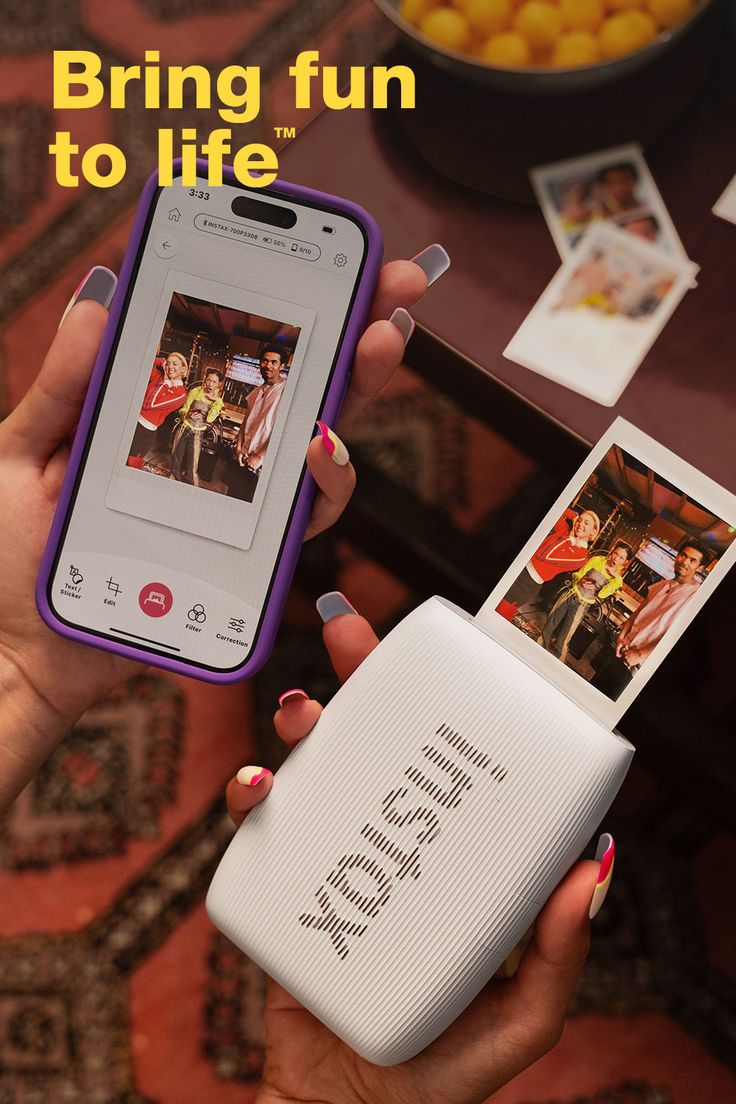 Hands holding a smartphone and a photo printer, printing an instant photo